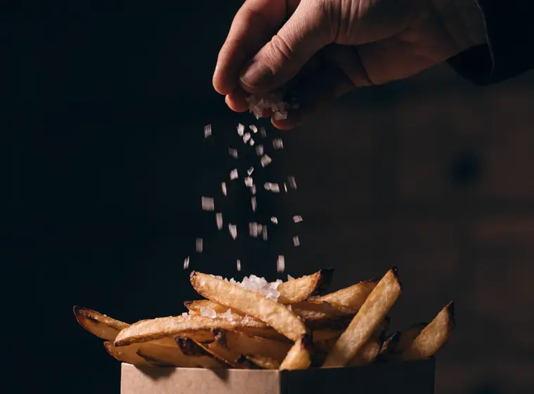 Frites maison salées à la volée au-dessus d'une barquette kraft
